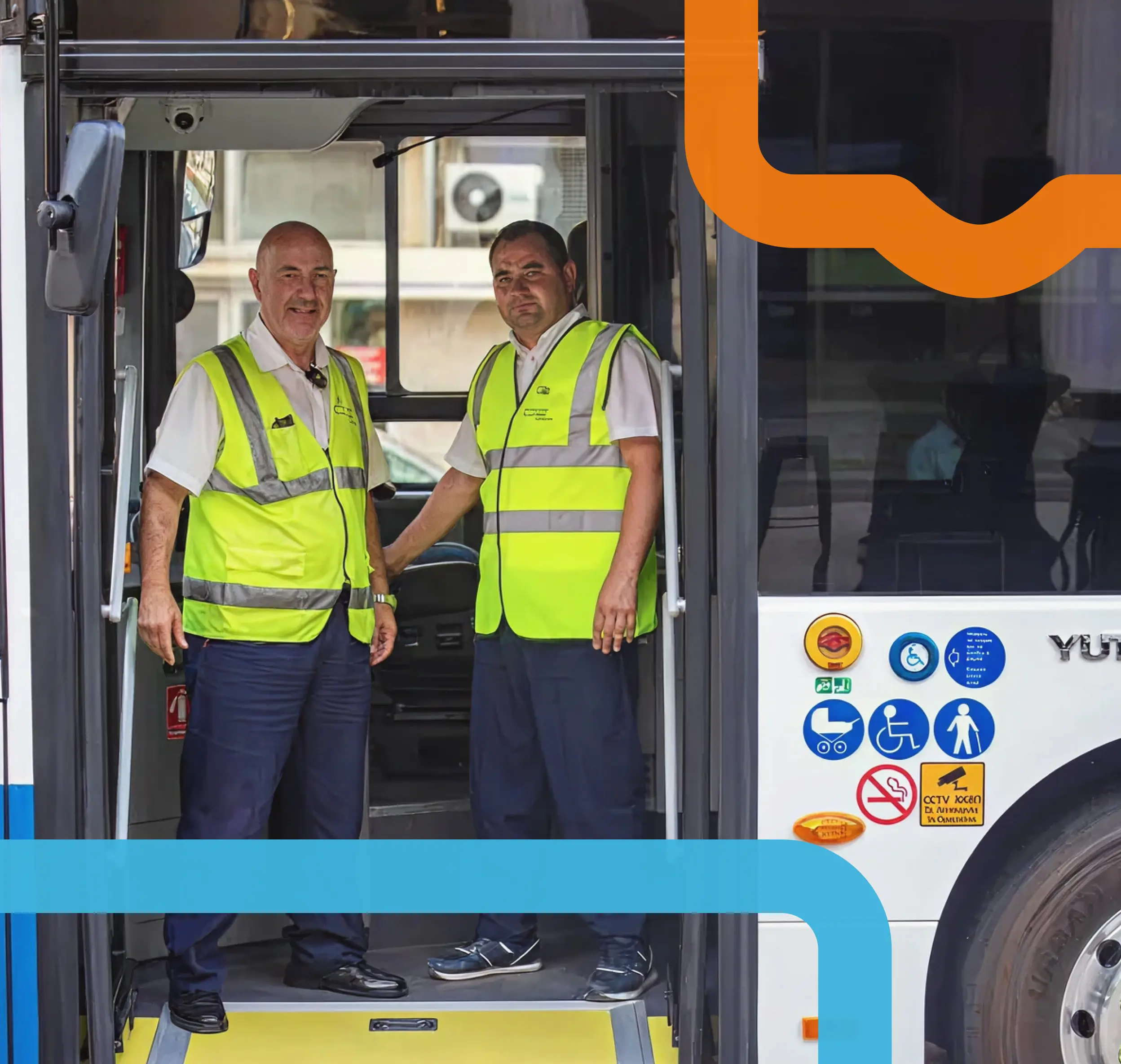 Two bus drivers in yellow reflective vests stand inside an open bus door, smiling. Accessibility and camera icons are visible on the bus.